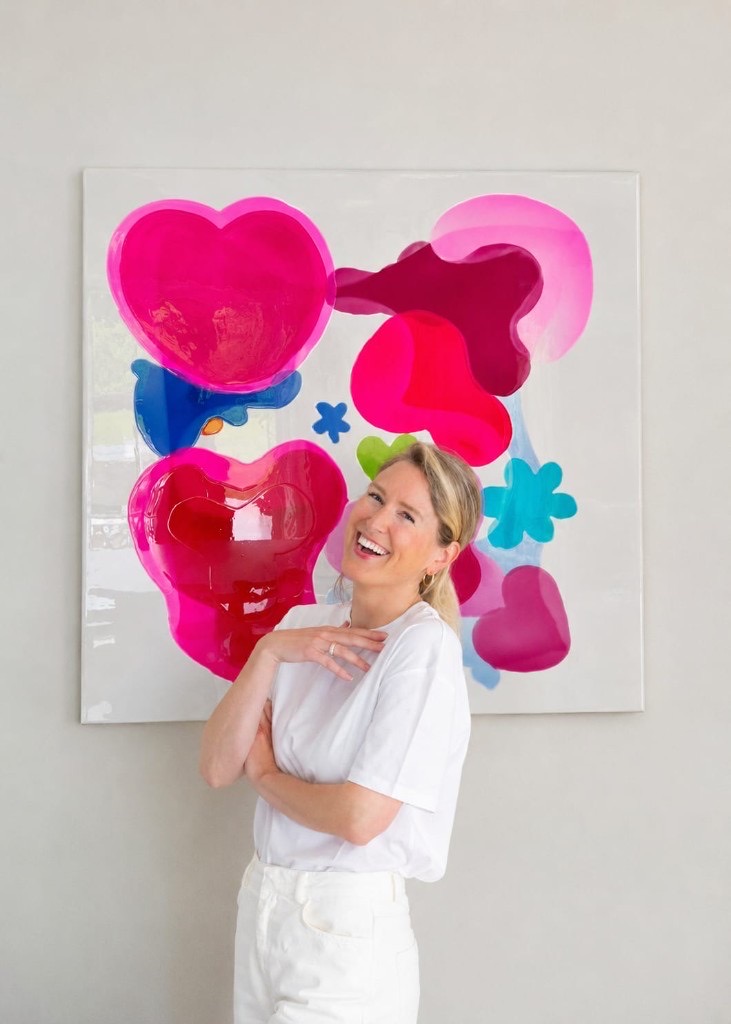Artist Valérie Parmentier beside one of her colourful resin heart-and-flower paintings